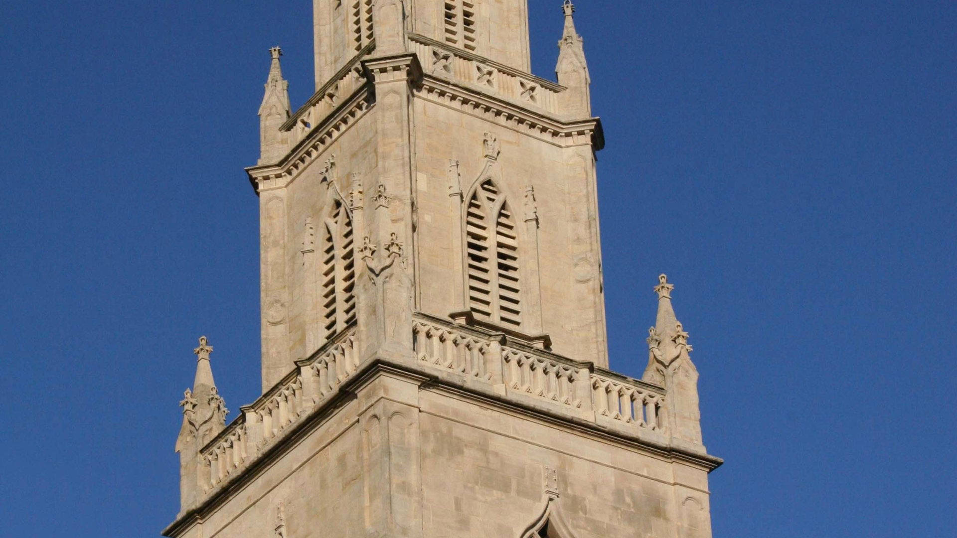 Close-up of St Paul's Church spire in Bristol, showing its tiered Georgian stonework against a clear blue sky