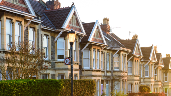 Row of Victorian terraced houses with bay windows and gabled roofs on a residential street, evening light.