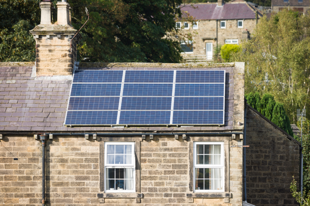 Solar panels installed on the slate roof of a traditional stone building, showing a heritage retrofit that adds renewable generation without altering the historic façade