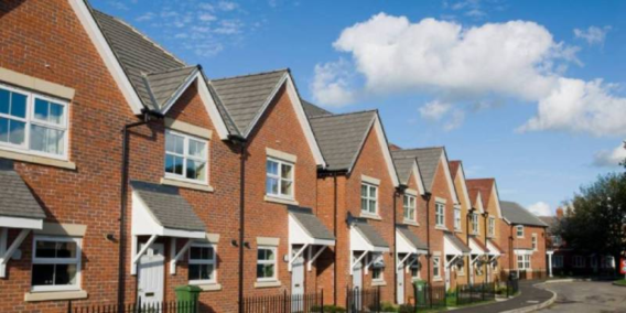 Modern red-brick terraced housing in North Warwickshire, with grey slate-effect roofs under a blue sky.