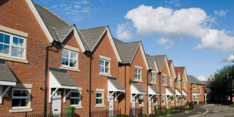 Modern red-brick terraced housing in North Warwickshire, with grey slate-effect roofs under a blue sky.